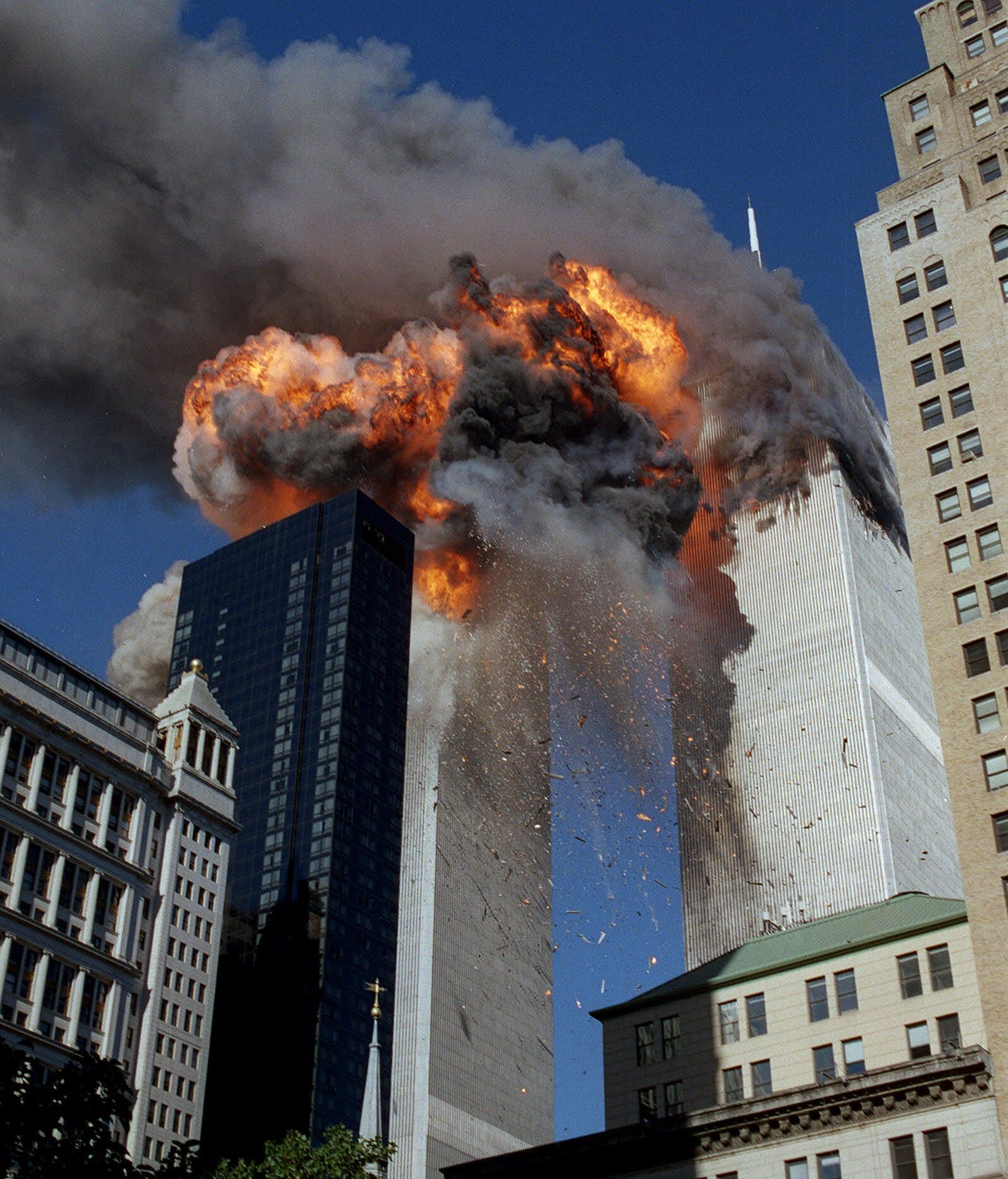 Smoke, flames and debris erupts from one of the World Trade Center towers as a plane strikes it in New York City on Sept. 11, 2001. The first tower was already burning following a terror attack minutes earlier. Terrorists crashed planes into the two buildings and collapsed both towers. (AP Photo/Chao Soi Cheong)