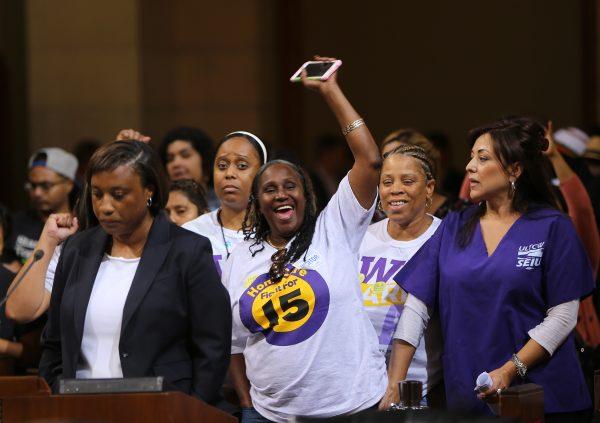 Laphonza Butler, president of SEIU ULTCW, the United Long Term Care Workers’ Union, far left, joins workers demanding that the Los Angeles City Council vote to raise the minimum wage on May 19, 2015. (AP Photo/Damian Dovarganes )