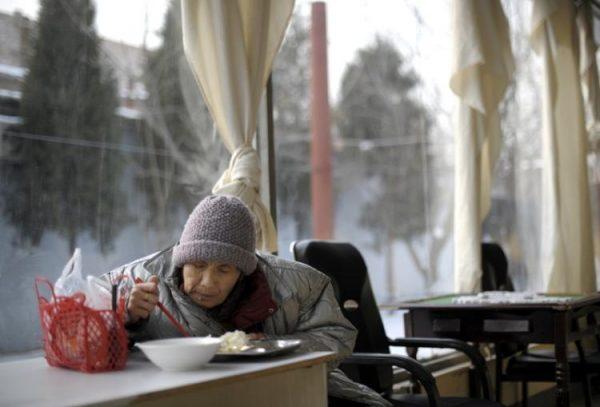 An elderly woman is eating a meal in a nursing home. China's one-child policy and aging heighten the shortage of elder care. (Liu Jin/AFP/Getty Images)