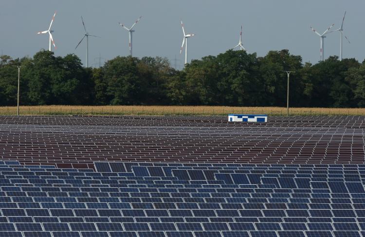 Renewable Energy: Wind turbines spin behind a field of solar cell panels. In 2010, investments in renewable energy sources, including wind, solar, and ocean power, will soar to $5 billion. (Sean Gallup/Getty Images)