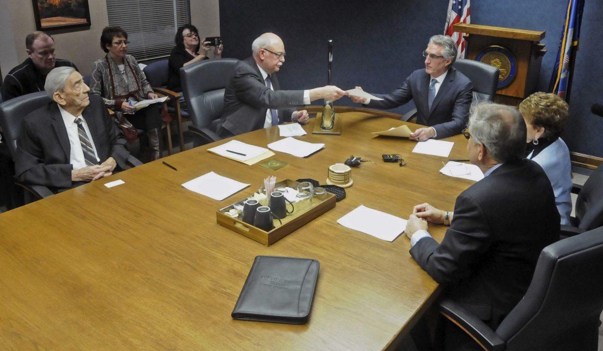 North Dakota Secretary of State Al Jaeger (L) hands Gov. Doug Burgum (C) voting results of the North Dakota Electoral College in Bismarck, N.D., on Dec. 19, 2016. (Tom Stromme/The Bismarck Tribune via AP)