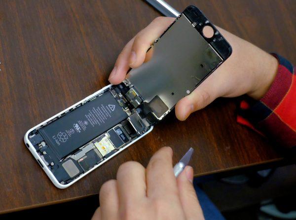 A battery is exposed as a man tries to repair an iPhone in a repair store in New York, Feb. 17, 2016. (Reuters/Eduardo Munoz/File Photo)