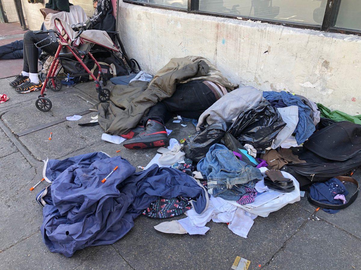Sleeping people, discarded clothes and used needles sit across the street from a staffed "Pit Stop" public toilet in the Tenderloin neighborhood in San Francisco, on July 25, 2019. (Janie Har/AP Photo)