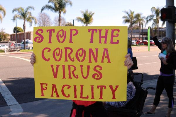 A protester holds up a sign near the Fairview Developmental Center in Costa Mesa, Calif., on Feb. 25, 2020. (Jamie Joseph/The Epoch Times)