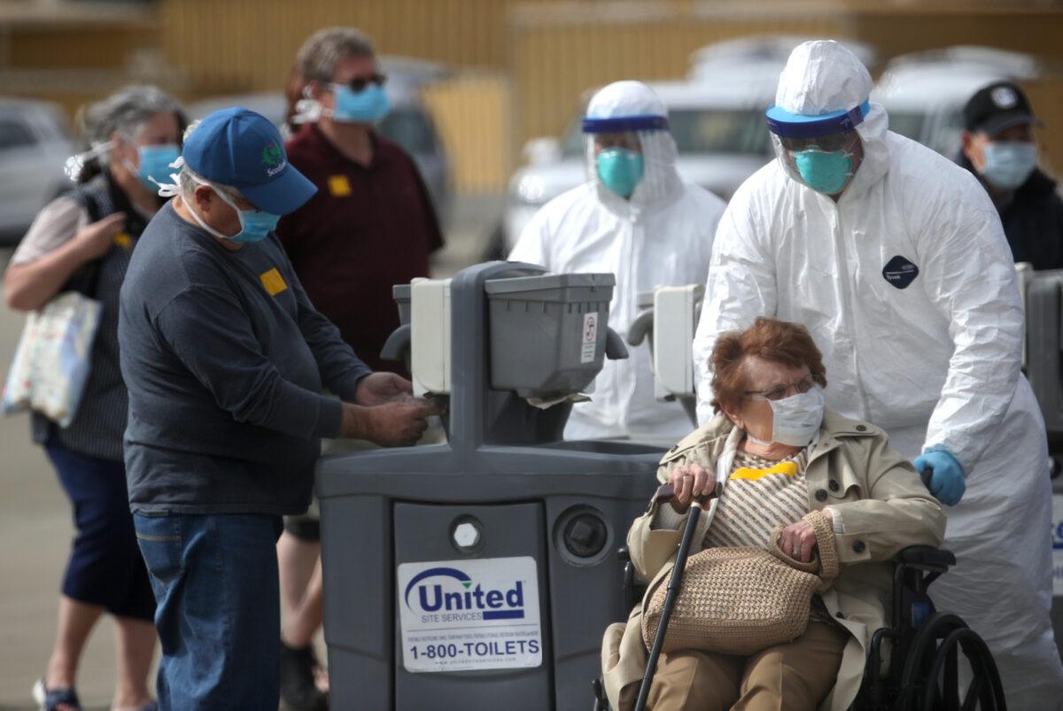 A medical worker assists a passenger from the Princess Cruises Grand Princess cruise ship before boarding a charter plane at Oakland International Airport in California on March 10, 2020. (Justin Sullivan/Getty Images)