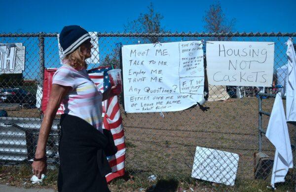 A woman walks past signs posted at the homeless encampment beside the Santa Ana River in Anaheim, Calif., on Feb. 20, 2018. (Frederic J. Brown/AFP via Getty Images)