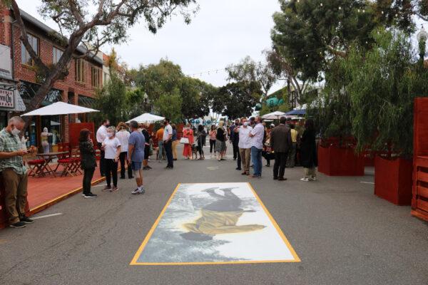 A crowd gathers amid installations by local artists and tables set up for neighborhood restaurants at the opening of the promenade in Laguna Beach, Calif., on June 15, 2020. (Jamie Joseph/The Epoch Times)
