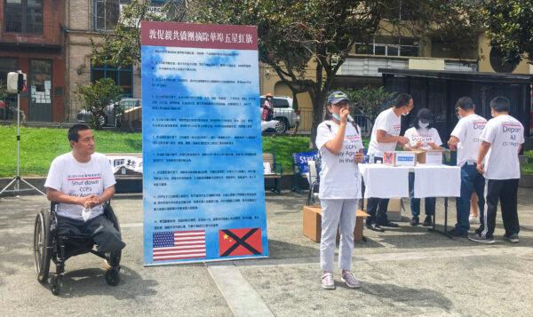 Fang Zheng (L) sits next to a banner that reads, “Urge pro-communist associations to remove the Five-Starred Red Flag.” (Ilene Eng/The Epoch Times)