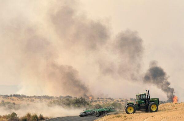A local man runs a tractor to carve out an impromptu fire line as the Pearl Hill fire moves closer to Mansfield, Wash., on Sept. 8, 2020. (Tyler Tjomsland/The Spokesman-Review via AP)