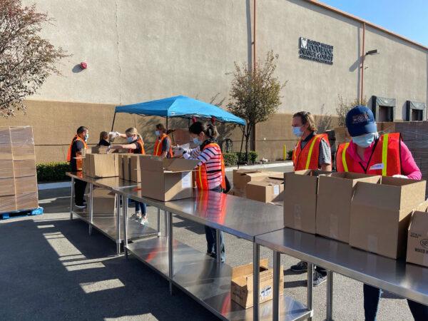 Volunteers stuff boxes with food for prepared Thanksgiving meals outside the Second Harvest Food Bank warehouse in Irvine, Calif., on Nov. 19, 2020. (Drew Van Voorhis/The Epoch Times)