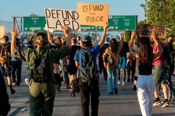 Protesters hold up signs as they block the freeway during a demonstration calling for defunding the police in Los Angeles, on July 1, 2020. (Valerie Macon/AFP via Getty Images)