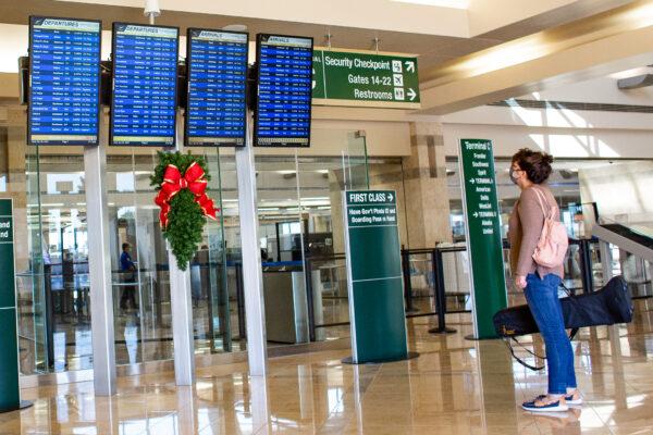 A passenger reads the flight board at John Wayne Airport in Orange County, Calif., on Dec. 30, 2020. (John Fredricks/The Epoch Times)