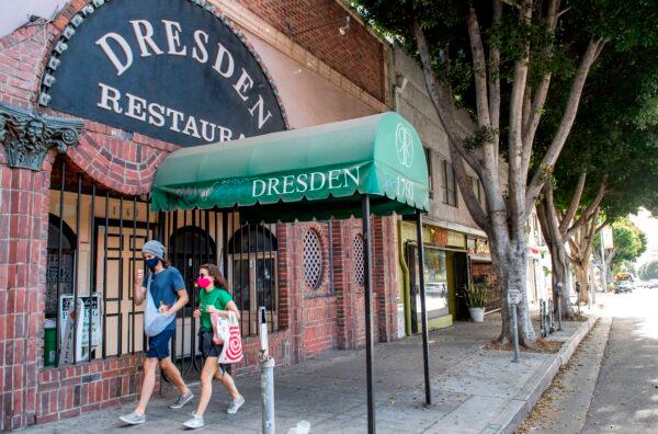 People wearing masks walk past a closed restaurant amid the CCP virus pandemic and the Stay-At-Home regulation underway in Los Angeles, Calif., on Dec. 8, 2020. (Valerie Macon/AFP via Getty Images)