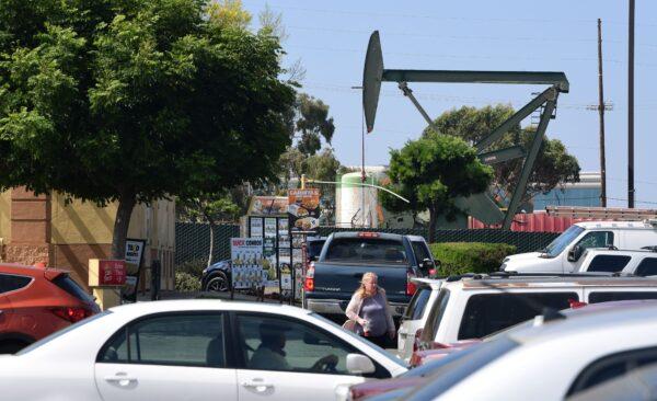 Motorists and pedestrians in a shipping plaza near an oil derrick pump in Signal Hill, Calif., on Sept. 25, 2019. (Frederic J. Brown/AFP via Getty Images)