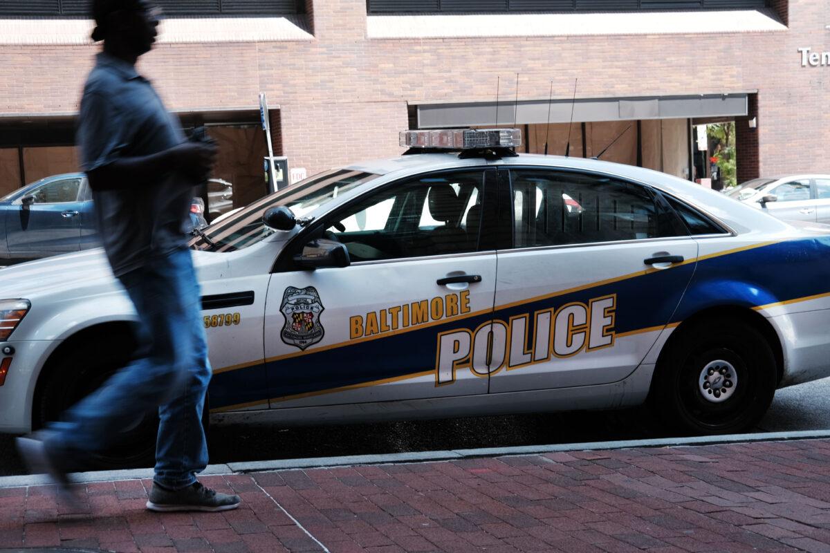 A person walks past a police car in Baltimore, Md., on July 28, 2019. (Spencer Platt/Getty Images)