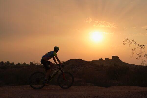 A cyclist bikes past the setting sun at Papago Park during a heatwave where temperatures hit 115-degrees in Phoenix, Arizona, on June 15, 2021. (AP Photo/Ross D. Franklin)