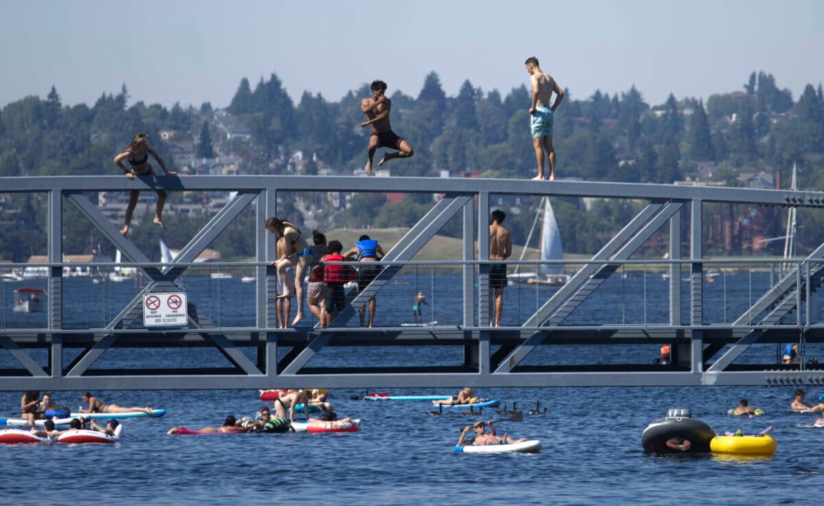 People jump into the water from a pedestrian bridge during a heat wave in the Pacific Northwest, at Lake Union Park in Seattle, on June 27, 2021. (John Froschauer/AP Photo)