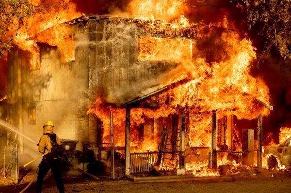 A firefighter sprays water while trying to stop the Sugar Fire, part of the Beckwourth Complex Fire, from spreading to neighboring homes in Doyle, Calif., on July 10, 2021. (Noah Berger/AP Photo)