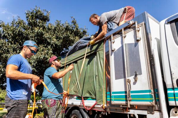 Water Wells for Africa Volunteers Chris Eggleston (L), and Daniel Dahlin (C) help Chris Treegarthen (R) tie down equipment on a truck before heading to Malawi's Machinga District on June 5, 2021. (John Fredricks/The Epoch Times)