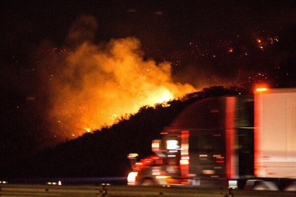 A vehicle passes by the burning Route fire, a brush wildfire off Interstate 5 north of Castaic, Calif., on Sept. 11, 2021. (Ringo H.W. Chiu/AP Photo)