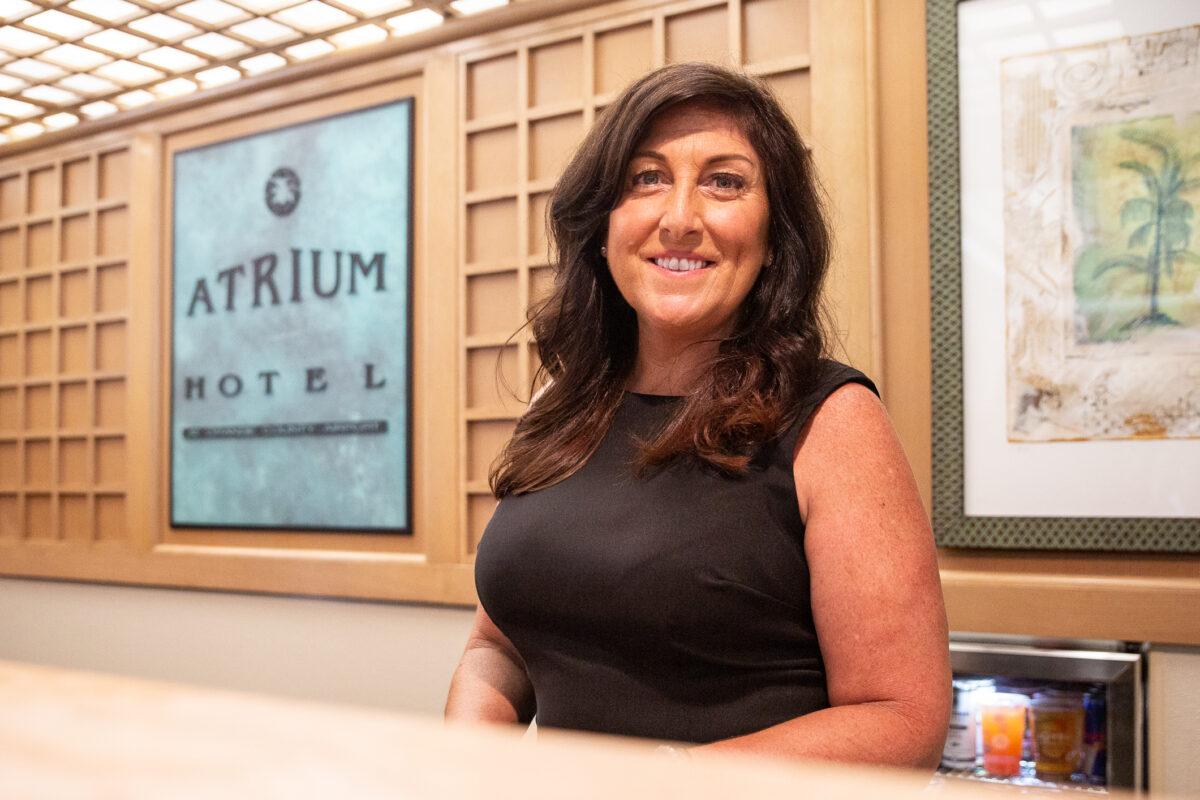 Tracy Newton stands at the front desk of the Atrium Hotel in Irvine, Calif., on Sept. 8, 2021. (John Fredricks/The Epoch Times)