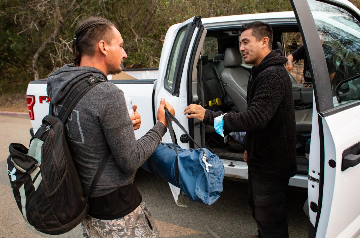 A LAHSA team member gives a homeless man a tent and a sleeping bag in Malibu, Calif., on Sept. 24, 2021. (John Fredricks/The Epoch Times)