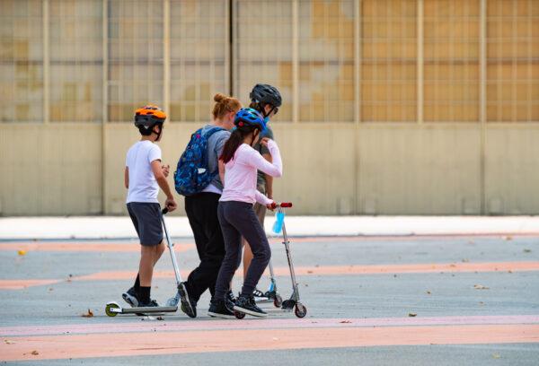 Kids and adults walk near old aircraft hangars in the Great Park, in Irvine, Calif., on July 17, 2020. (John Fredricks/The Epoch Times