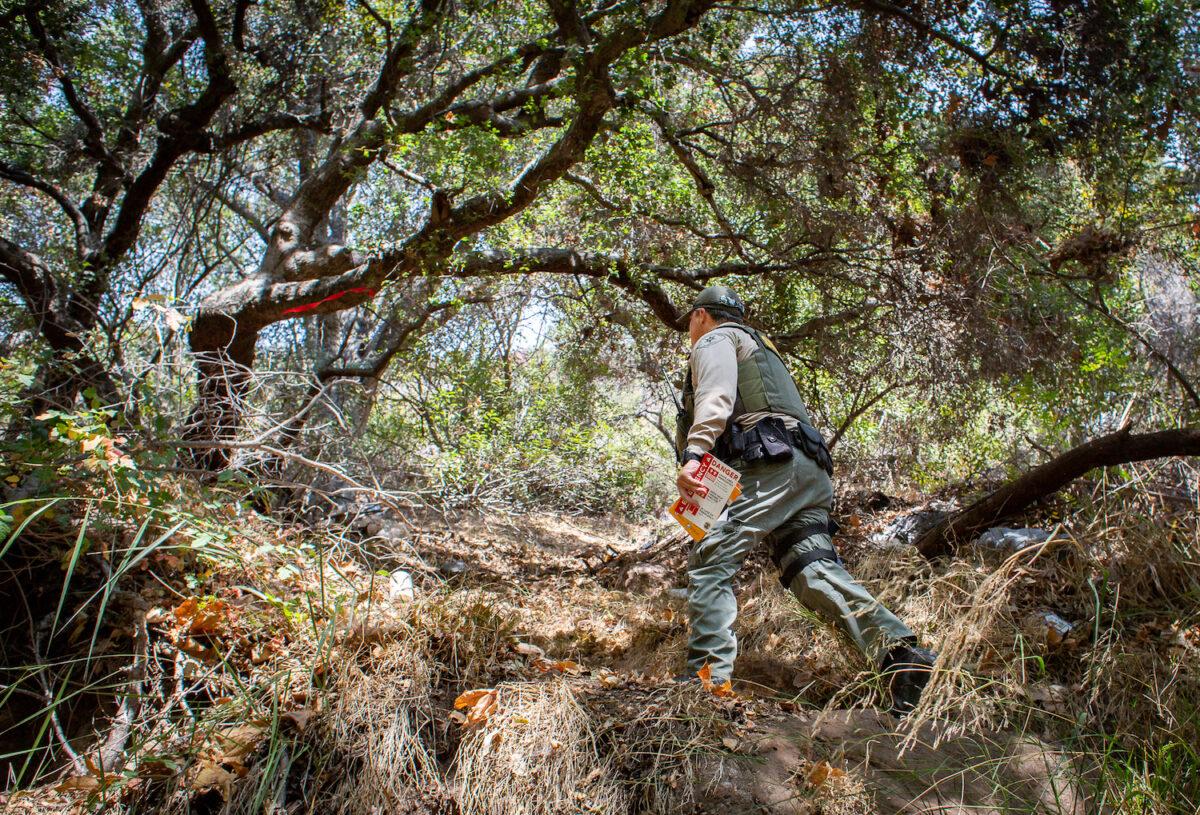 A Los Angeles Sheriff's Department Homeless Outreach Services Team deputy checks on a homeless encampment in Malibu, Calif., on Sept. 24, 2021. (John Fredricks/The Epoch Times)