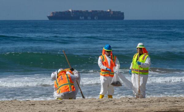 Workers clean an oil spill along the coastline in Huntington Beach, Calif., on Oct. 5, 2021. (John Fredricks/The Epoch Times)