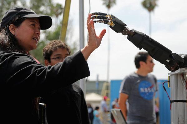 A woman reaches to touch a robotic arm developed by the Johns Hopkins University Applied Physics Laboratory on display at the DARPA Robotics Challenge Expo at the Fairplex in Pomona, California, on June 6, 2015. (Chip Somodevilla/Getty Images)