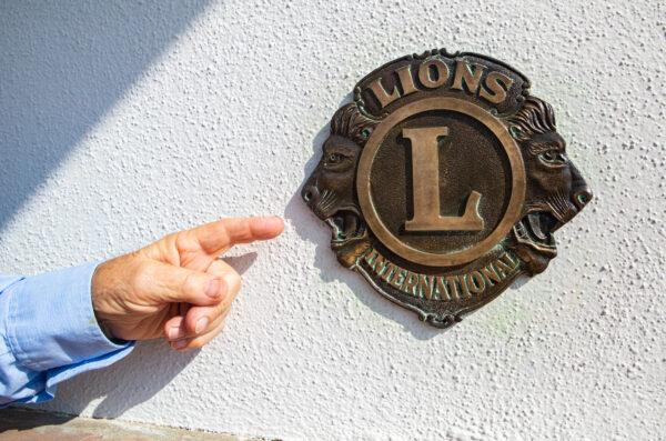 Fullerton Lions Club member Matyas "Matt" Hunyadi points to a Lions Club sign in Fullerton, Calif., on Nov. 9, 2021. (John Fredricks/The Epoch Times)