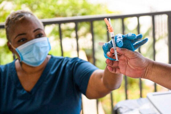 A nurse is handed a dose of the Pfizer COVID-19 vaccine before administering it to a college student at a mobile vaccination clinic at the California State University Long Beach campus in Calif., on Aug. 11, 2021. (Patrick T. Fallon/AFP via Getty Images)