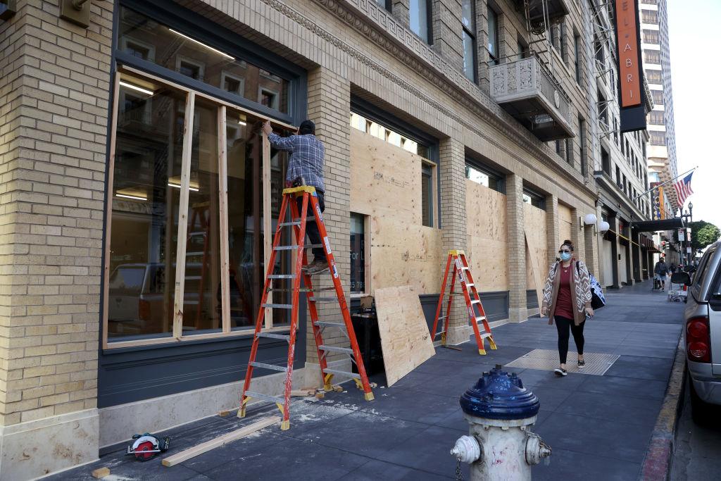 A worker hangs plywood on the exterior of a closed business in San Francisco, Calif., on April 16, 2021. (Justin Sullivan/Getty Images)