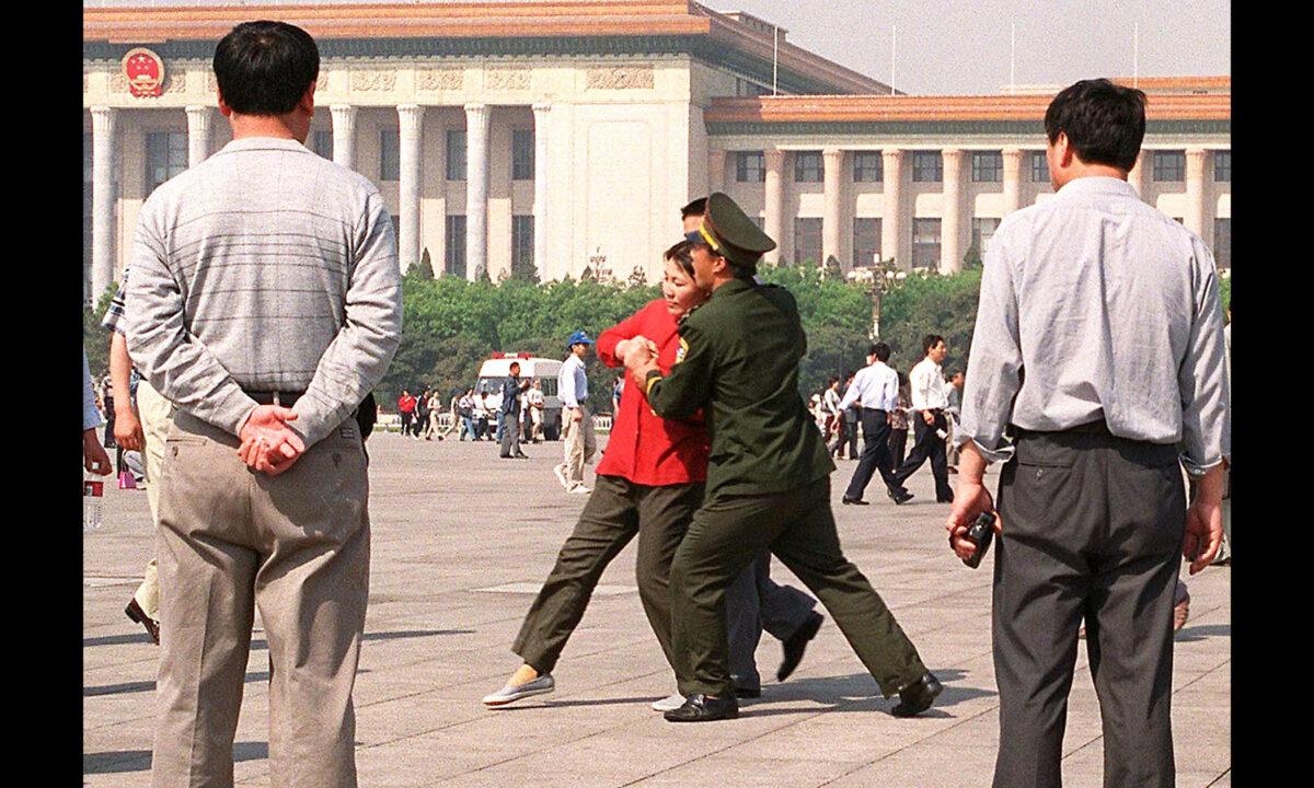 A Falun Gong practitioner is forcefully taken away by Chinese police towards a police van in Tiananmen Square in Beijing, China, on May 11, 2000. (Stephen Shaver/AFP via Getty Images)
