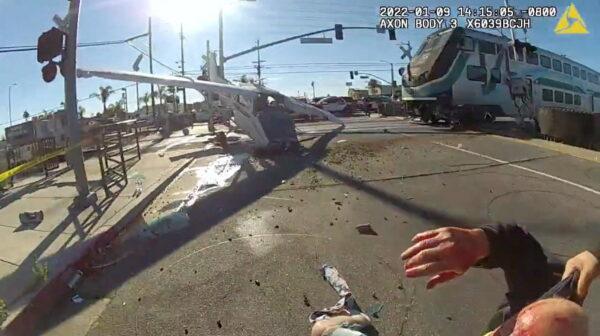 A screen grab from a police body camera video shows the pilot of a plane that crashed on railway tracks being rescued by Los Angeles Police Department officers moments before a train hit the aircraft in Los Angeles, Calif., on Jan. 9, 2022. (LAPD/Handout via Reuters)