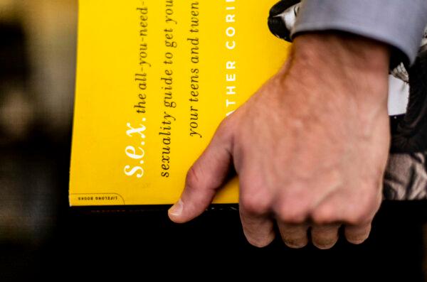 A man holds a book on sex in Irvine, Calif., on Jan. 17, 2022. (John Fredricks/The Epoch Times)