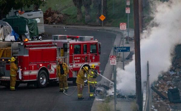 A team with the Los Angeles Fire Department extinguishes multiple small fires set in homeless camps in Los Angeles on Jan. 20, 2022. (John Fredricks/The Epoch Times)