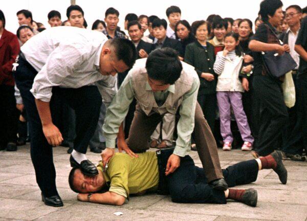 Police detain a Falun Gong practitioner in Tiananmen Square as a crowd watches in Beijing, China, on Oct. 1, 2000 photo. (Chien-min Chung/AP Photo)