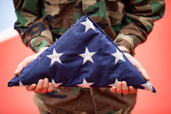 A file photo of a child holding an American Flag while wearing a Marine uniform in La Puente, Calif., on Jan. 19, 2021. (John Fredricks/The Epoch Times)