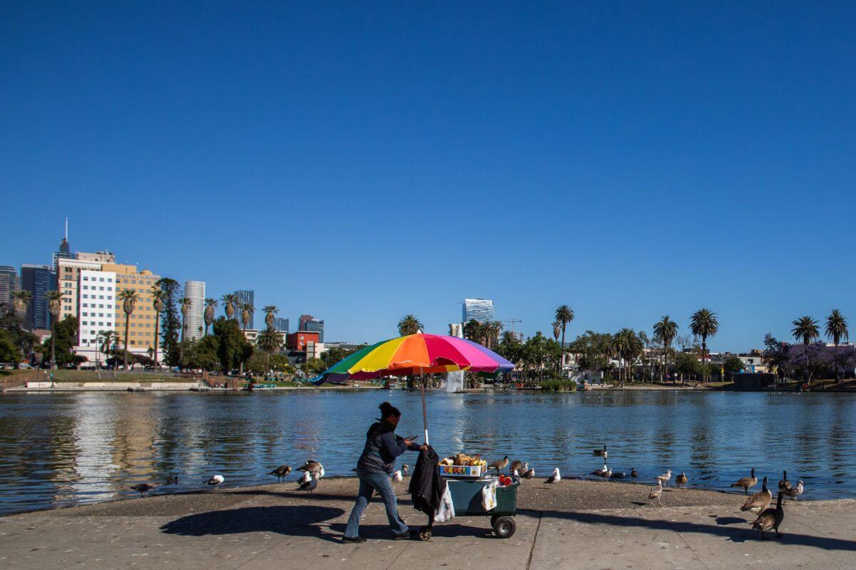 A street vendor pushes her cart in MacArthur Park in Los Angeles on May 21, 2020. (Apu Gomes/AFP via Getty Images)