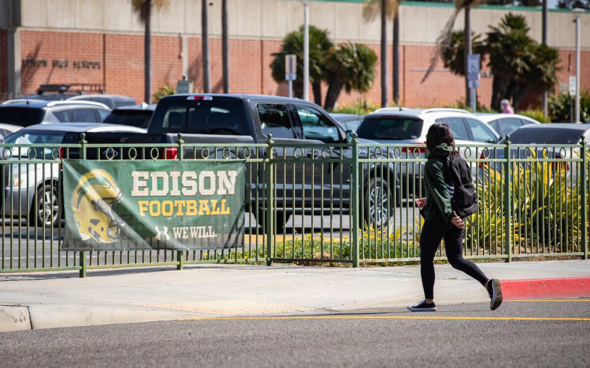 A student walks past a sign for the school's football team at Edison Highschool in Huntington Beach, Calif., on March 10, 2022. (John Fredricks/The Epoch Times)