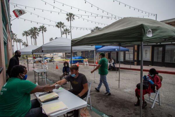 Homeless people wait to be checked-in to a hotel room in Venice Beach, Calif., on April 26, 2020. (Apu Gomes/AFP via Getty Images)