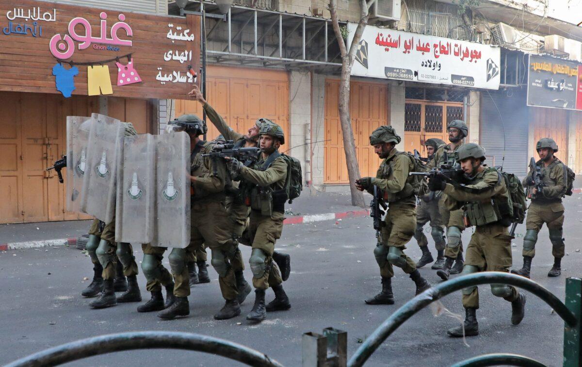 Israeli army soldiers with riot shields approach Palestinian protesters during clashes following a demonstration to denounce the annual nationalist "flag march" through Jerusalem, in the city of Hebron in Judea on the West Bank on May 29, 2022. (Mosab Shawer/AFP via Getty Images)