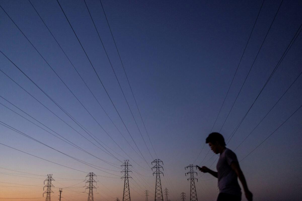 A man walks by power lines, as California's grid operator urged the state's 40 million people to ratchet down the use of electricity in homes and businesses as a heat wave settled over much of the state, in Mountain View, Calif., on Aug. 17, 2022. (Carlos Barria/Reuters)