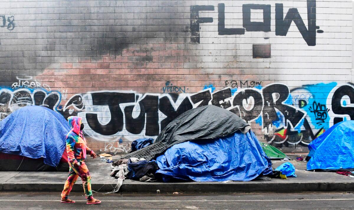 A woman walks past tents for the homeless lining a street in Los Angeles, Calif., on Feb. 1, 2021. (Frederic J. Brown/AFP via Getty Images)