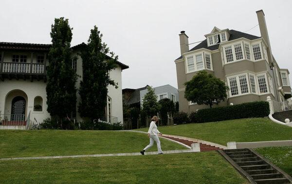 A woman walks past luxury homes in the Sea Cliff neighborhood of San Francisco on May 26, 2005. (Justin Sullivan/Getty Images)