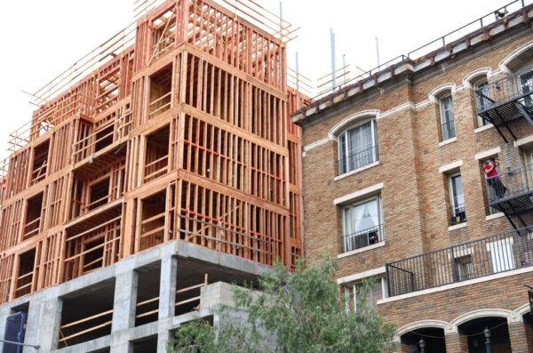 A person stands on a balcony next to new residential units under construction in Los Angeles on Aug. 4, 2022. (Mario Tama/Getty Images)