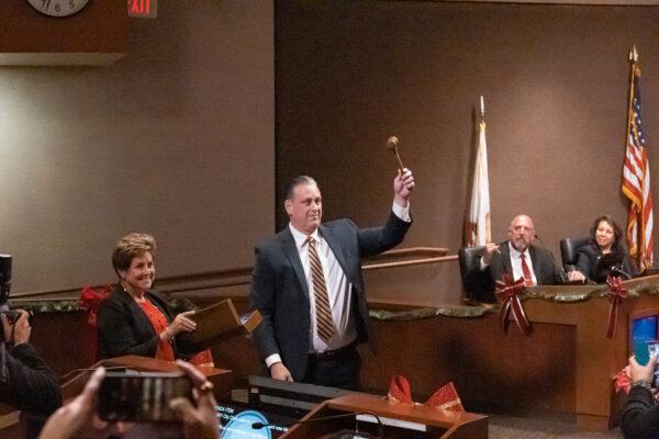 Former Mayor Barbara Delgleize presents incoming Mayor Tony Strickland with a gavel to celebrate his newly elected position. In exchange, Strickland gave Delgleize an award depicting a surfer on a big wave, showing gratitude for her time in office in Huntington Beach, Calif., on Dec. 6, 2022. (Julianne Foster/The Epoch Times)