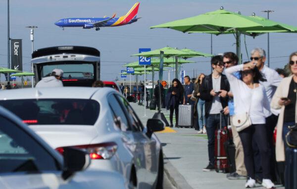 Arriving passengers wait to board Uber vehicles at the new 'LAX-it' ride-hail passenger pickup lot, as a Southwest Airlines plane lands, at Los Angeles International Airport (LAX) in Los Angeles, on Nov. 6, 2019. (Mario Tama/Getty Images)