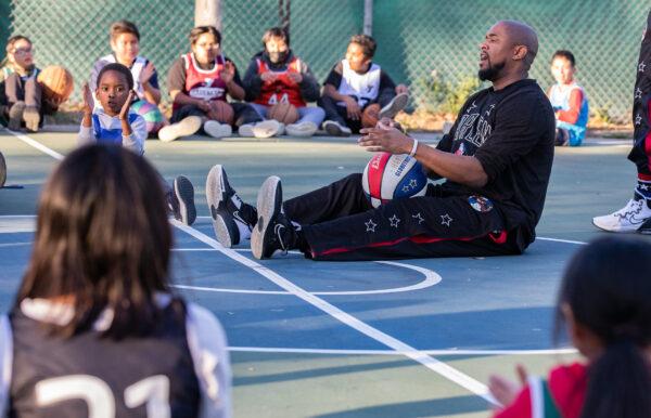 Harlem Globetrotter Shane "Scooter" Christensen leads children as they take part in a one-hour basketball training session hosted by the YMCA of Orange County in Fullerton, Calif., on Feb. 1, 2023. (John Fredricks/The Epoch Times)